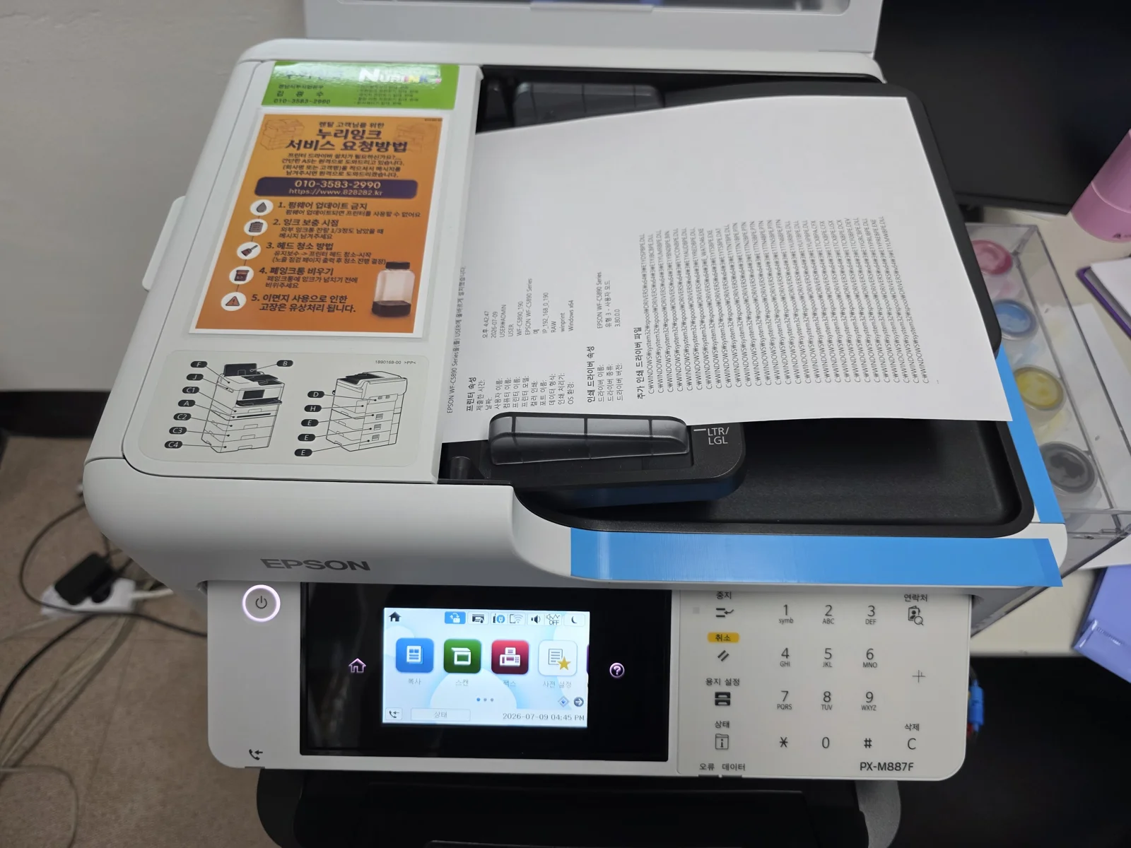 ADF에 A4 용지를 넣고 스캔 테스트를 준비하는 EPSON 복합기, 사용방법 안내지가 붙은 모습
