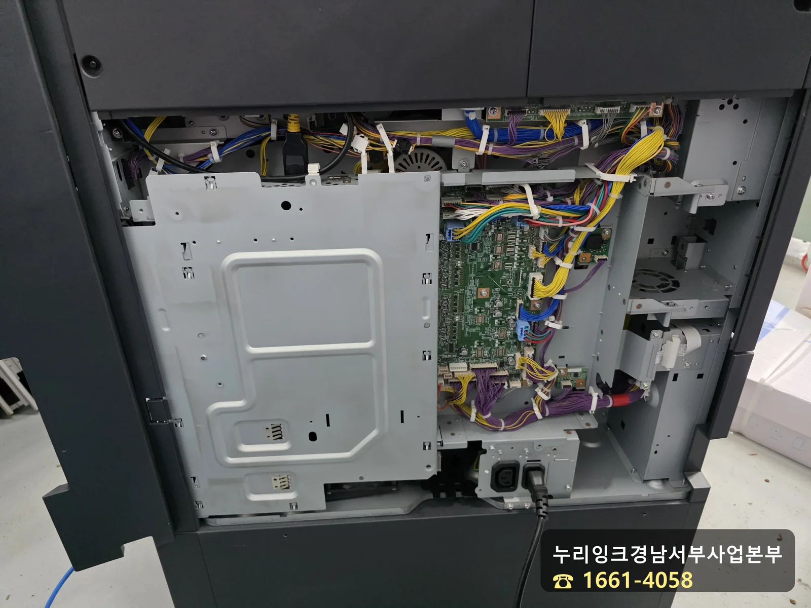 복사기 뒷면 넓은 플라스틱 커버를 제거하고 내부 배선과 기판을 노출시킨 모습