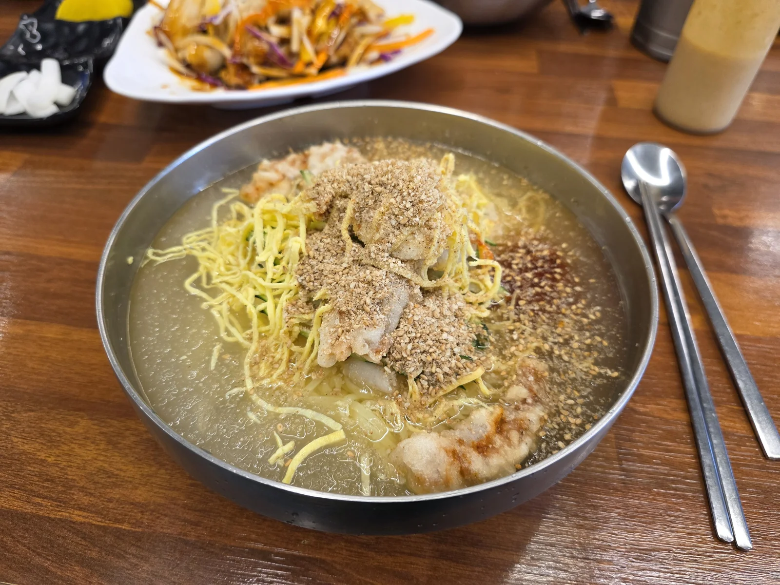지단채와 깨가루 고명이 올라간 수타 밀면 한 그릇