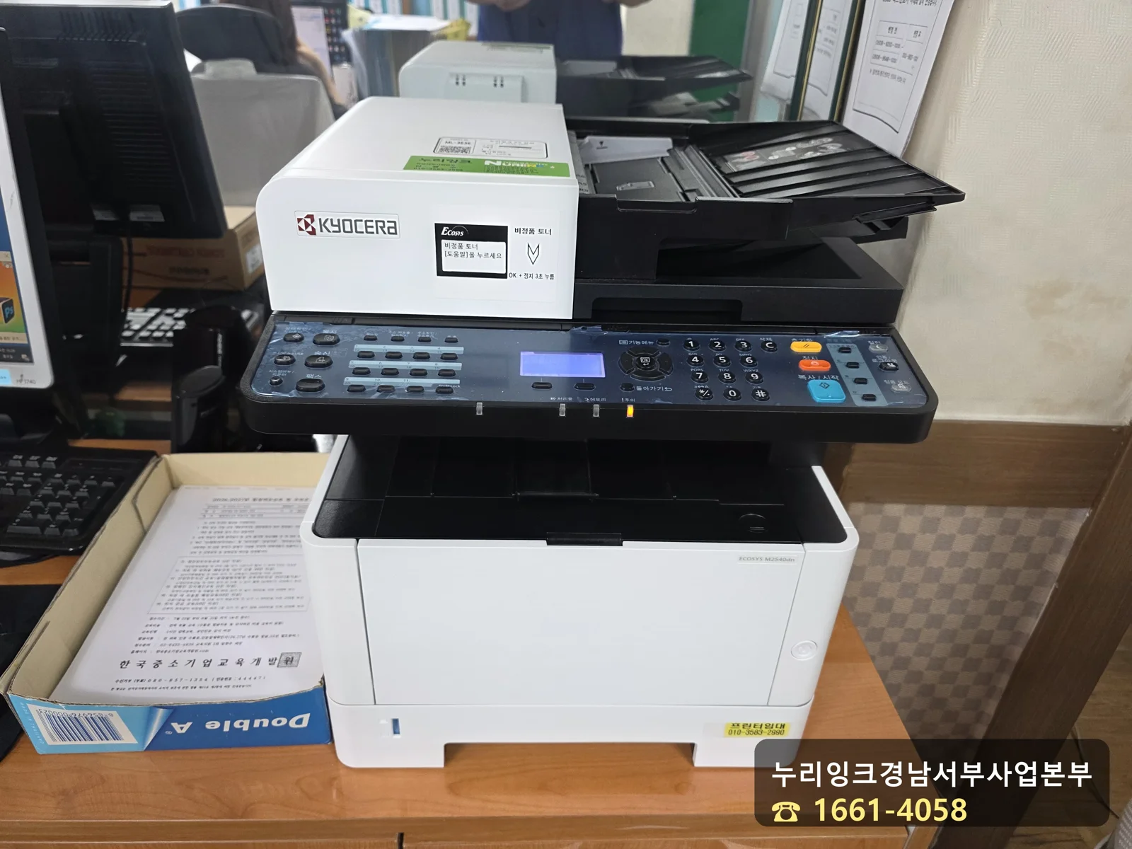 교세라 ECOSYS M2540dn 복합기와 새 토너 컨테이너, 사무실 책상 위 설치 모습